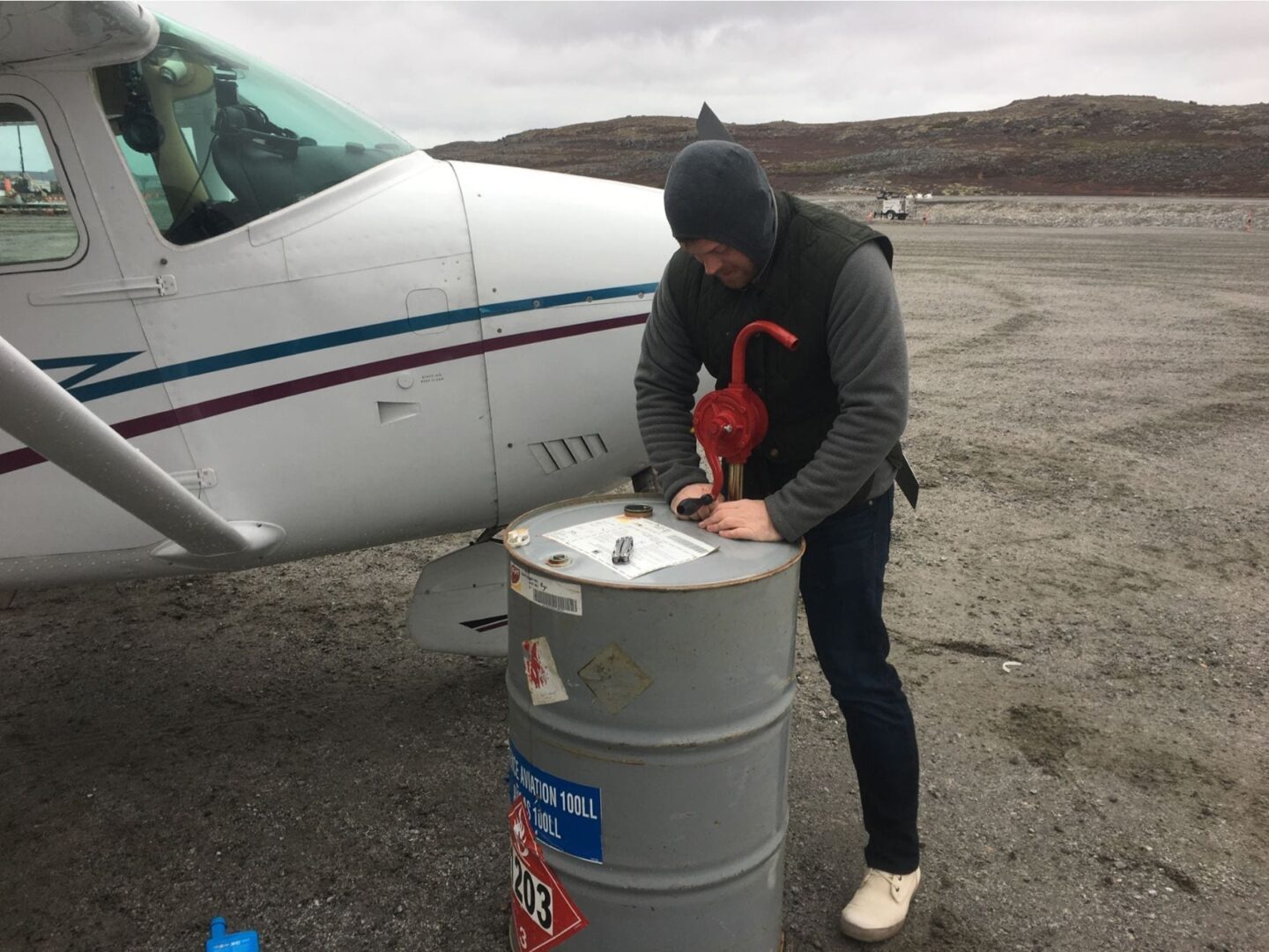 A man in black jacket standing next to an airplane.